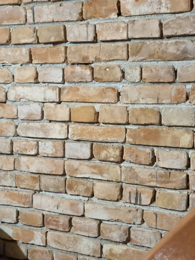 Perete de cărămidă aparentă într-un beci de gospodărie, cu balustradă de lemn