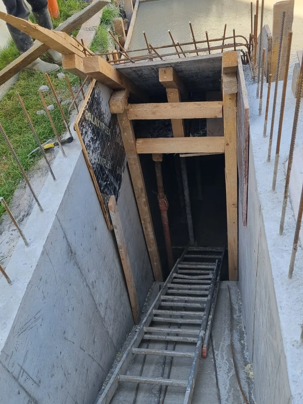 Intrare de beci construită pe un teren în pantă, cu scară de acces, văzută de sus