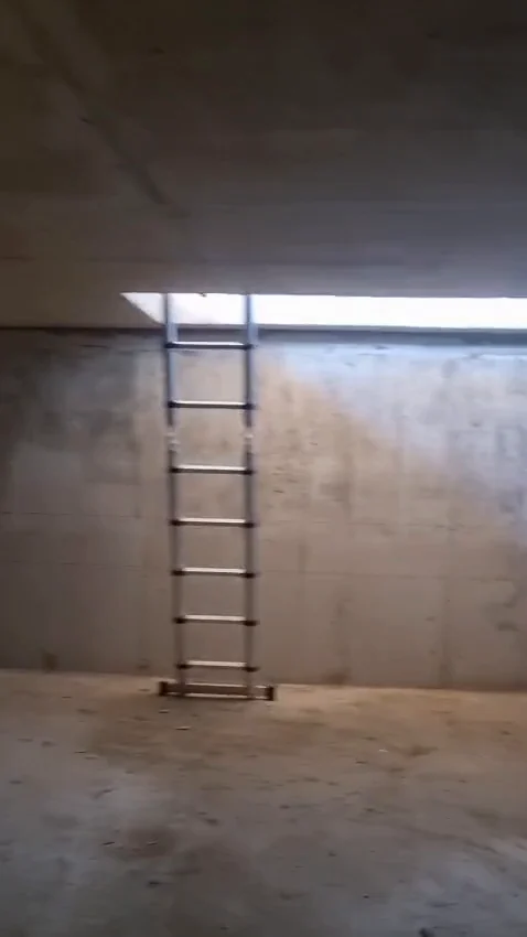 Interiorul unui beci finalizat, cu pereți de beton și scara de acces spre trapă